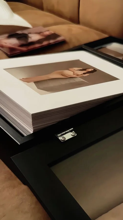 A stack of professional museum-grade matted maternity portraits in a black presentation box, featuring high-contrast editorial studio photography.