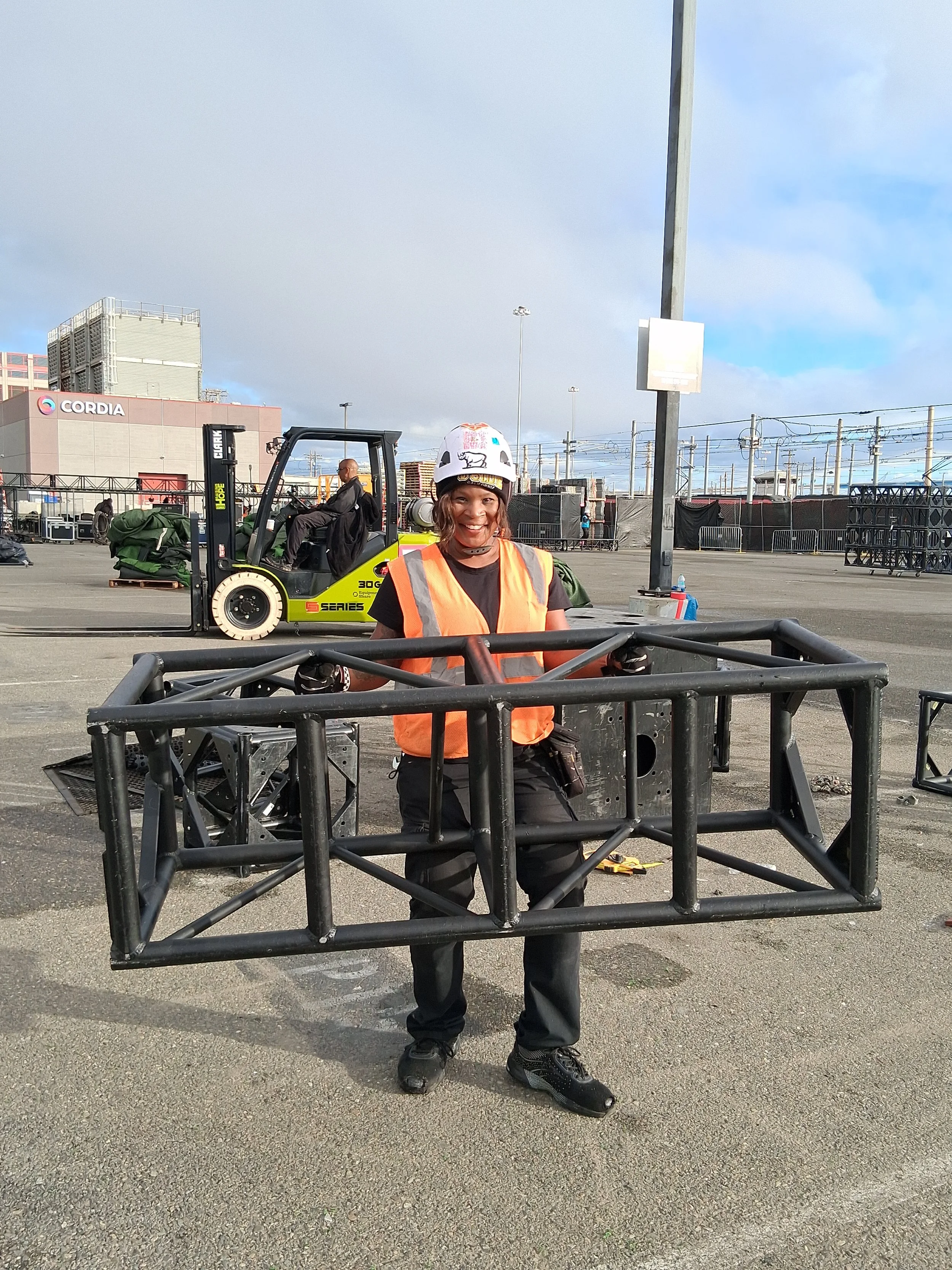 Professional stagehand and camera operator managing live event production equipment, including lighting rigs, cameras, and staging setup in a high-energy concert environment in San Diego. Truess build stagehand