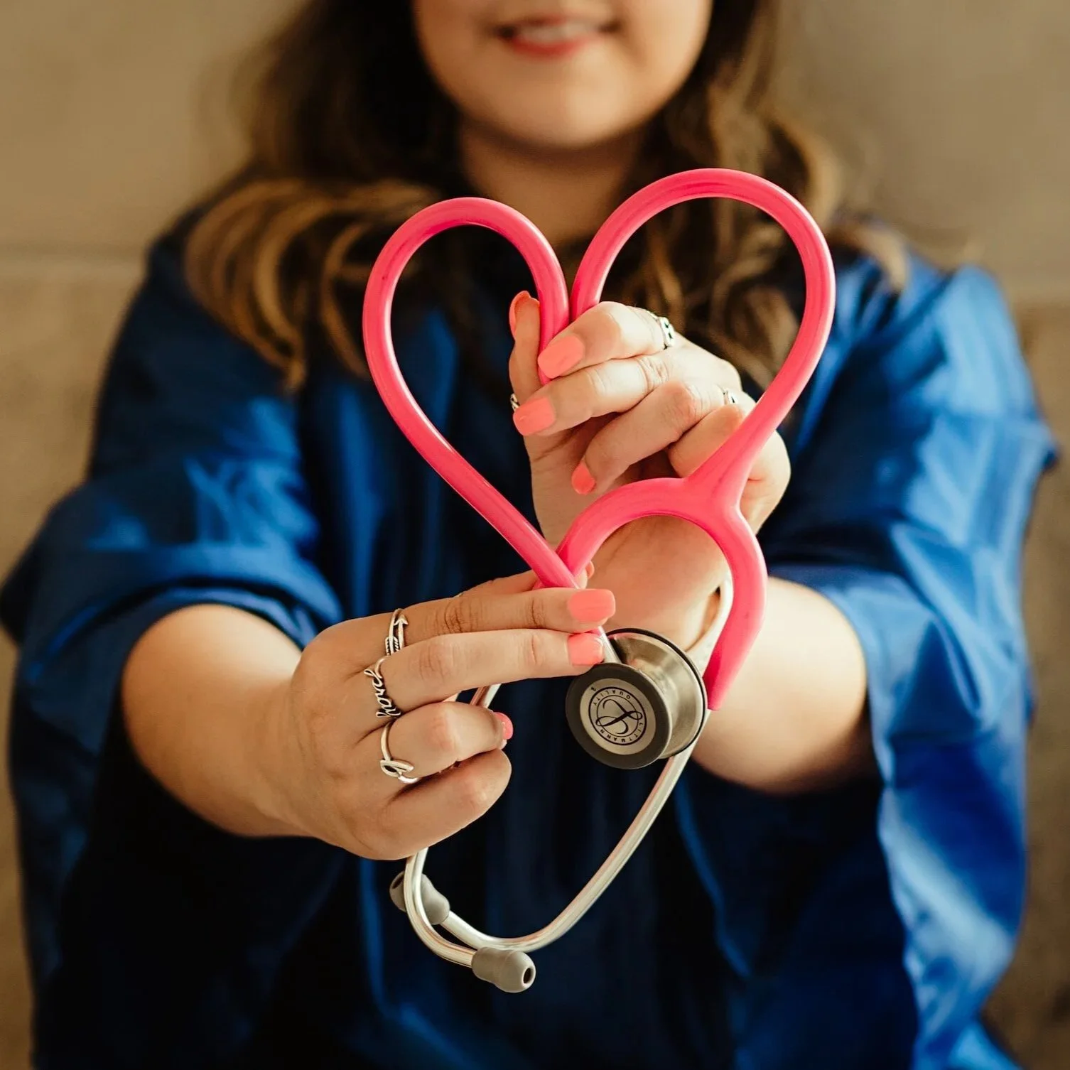 Physician holding a pink stethoscope shaped like a heart