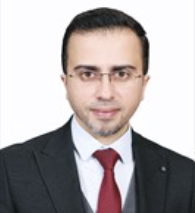 Front-facing headshot of a bespectacled Palestinian academic in a black suit, white shirt, and red tie