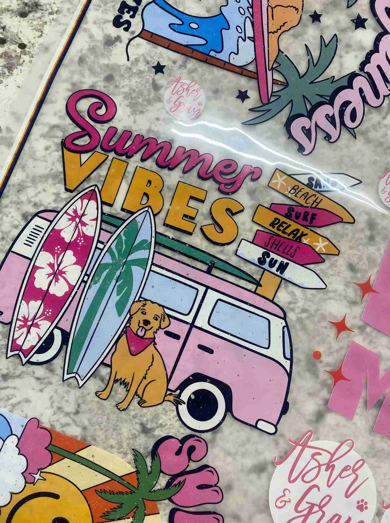 A colorful summer-themed sticker featuring a pink van with two surfboards, one with a pink and white floral design and the other with a green and white leaf pattern. A cheerful golden retriever wearing a pink bandana sits beside the van. There are si