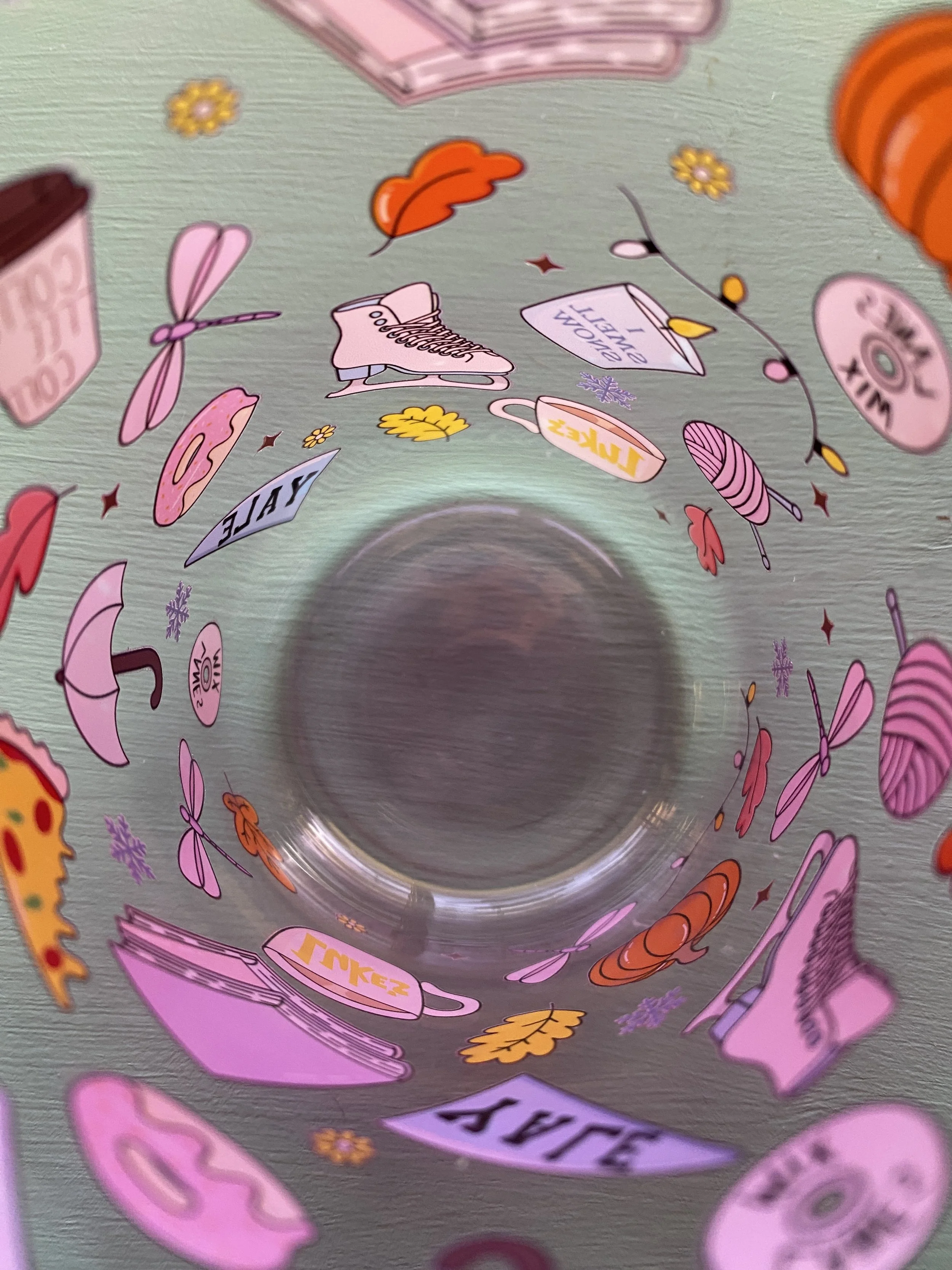 Inside view of a clear glass with various colorful stickers attached, featuring food, beverages, and playful illustrations.