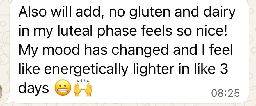 Screenshot of a message stating improved mood and energy after avoiding gluten and dairy in the luteal phase, with emojis including a smiling face and raised hands.