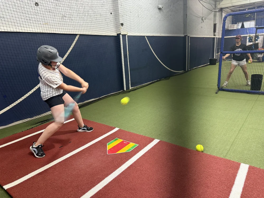 Young softball player practicing batting inside Swing Zone