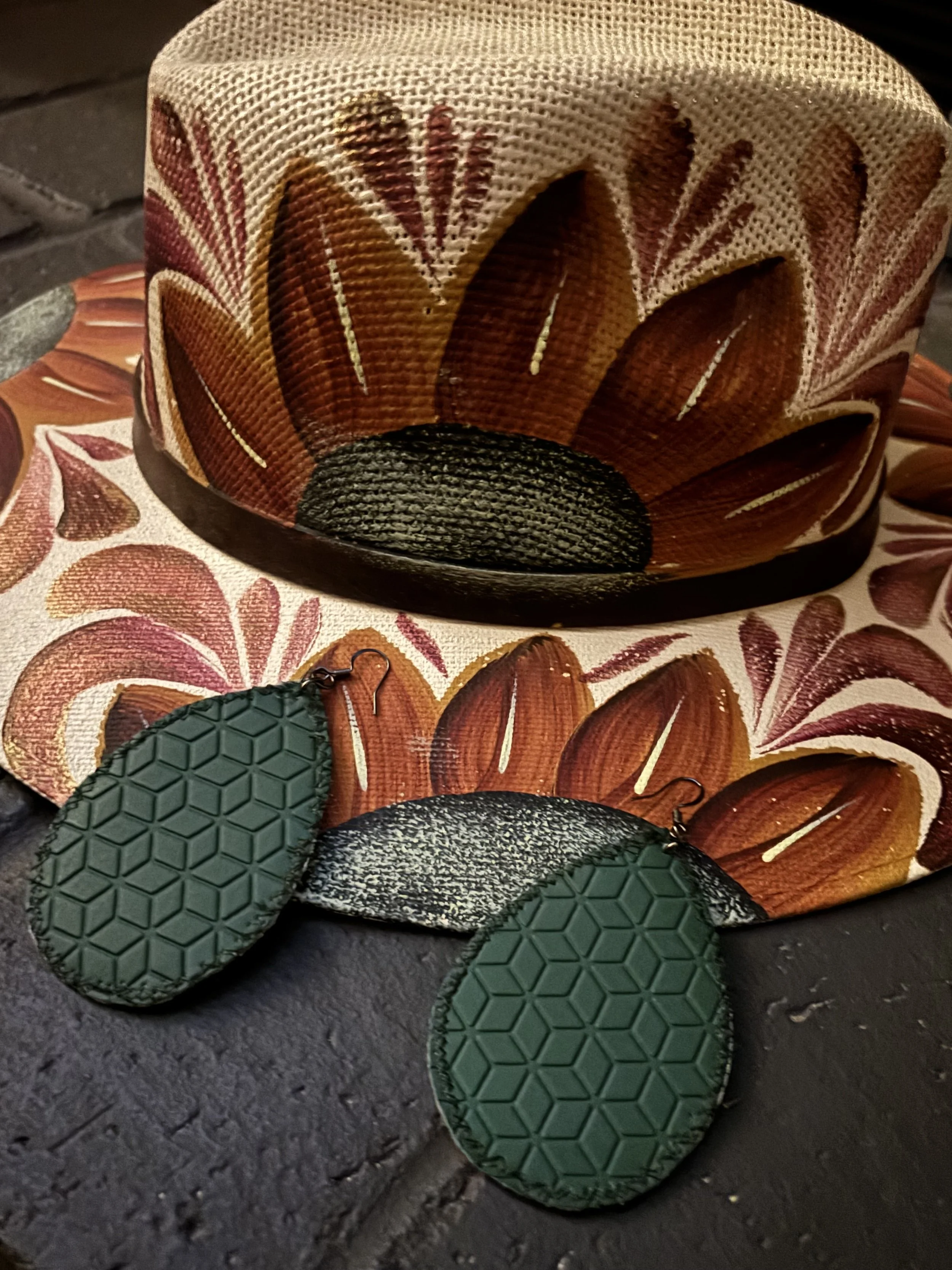 Decorative fabric lampshade with a floral pattern in shades of brown, red, and white, sitting on a wooden surface with a pair of green rubber-soled shoes nearby.