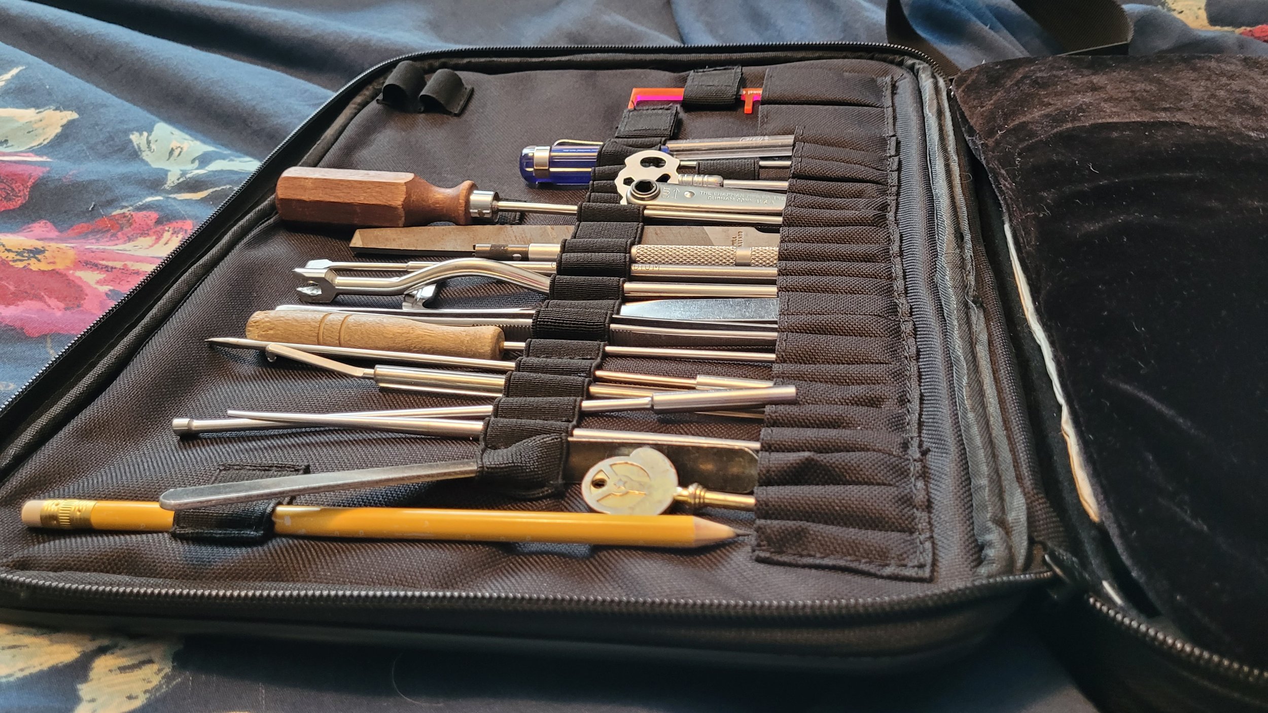 A professional piano technician's tool bag neatly organized with piano tuning levers, mutes, and specialized maintenance tools.