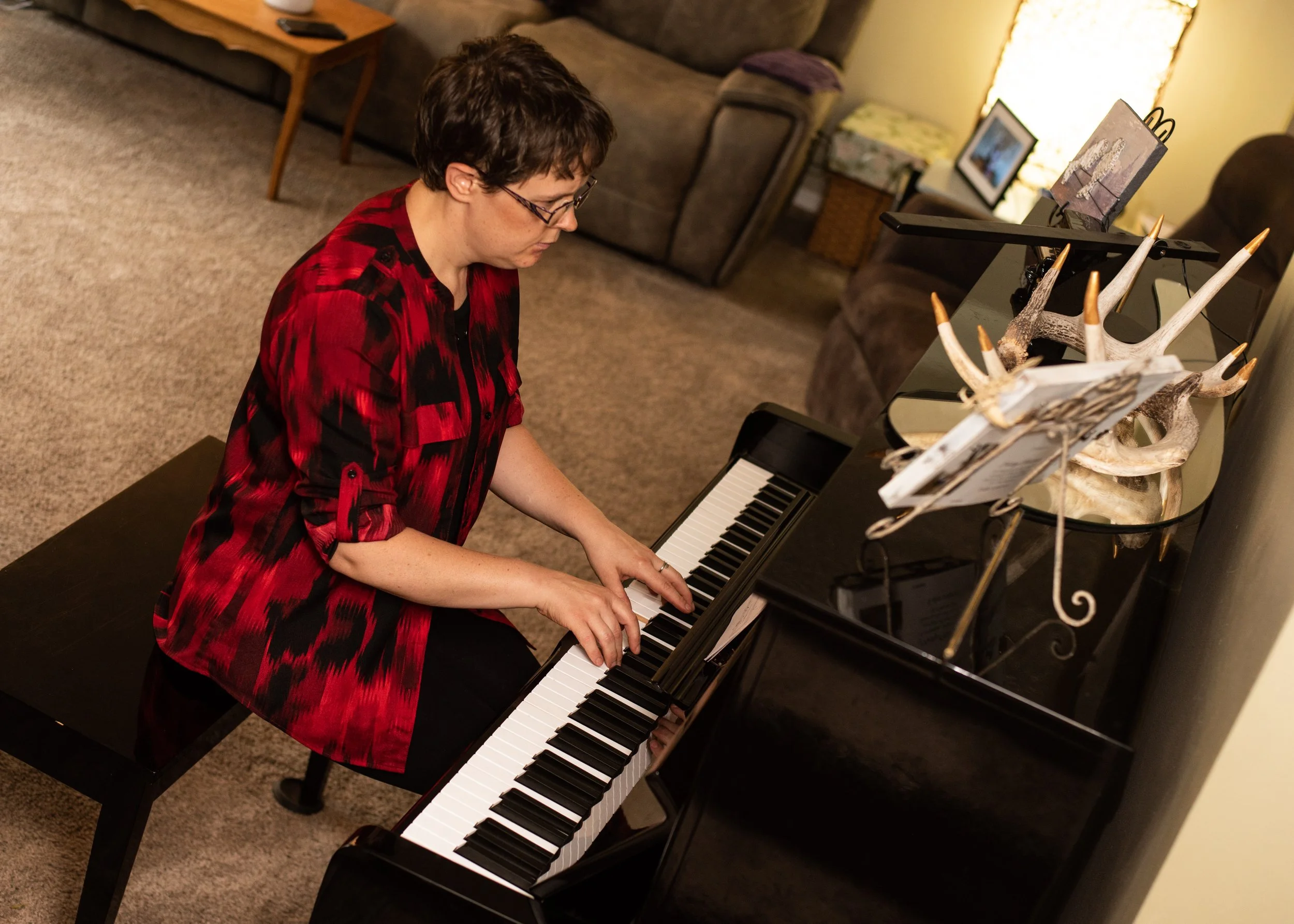 Registered Piano Technician Audi Lou Nordby sitting at an upright piano in Saskatchewan playing the keys.