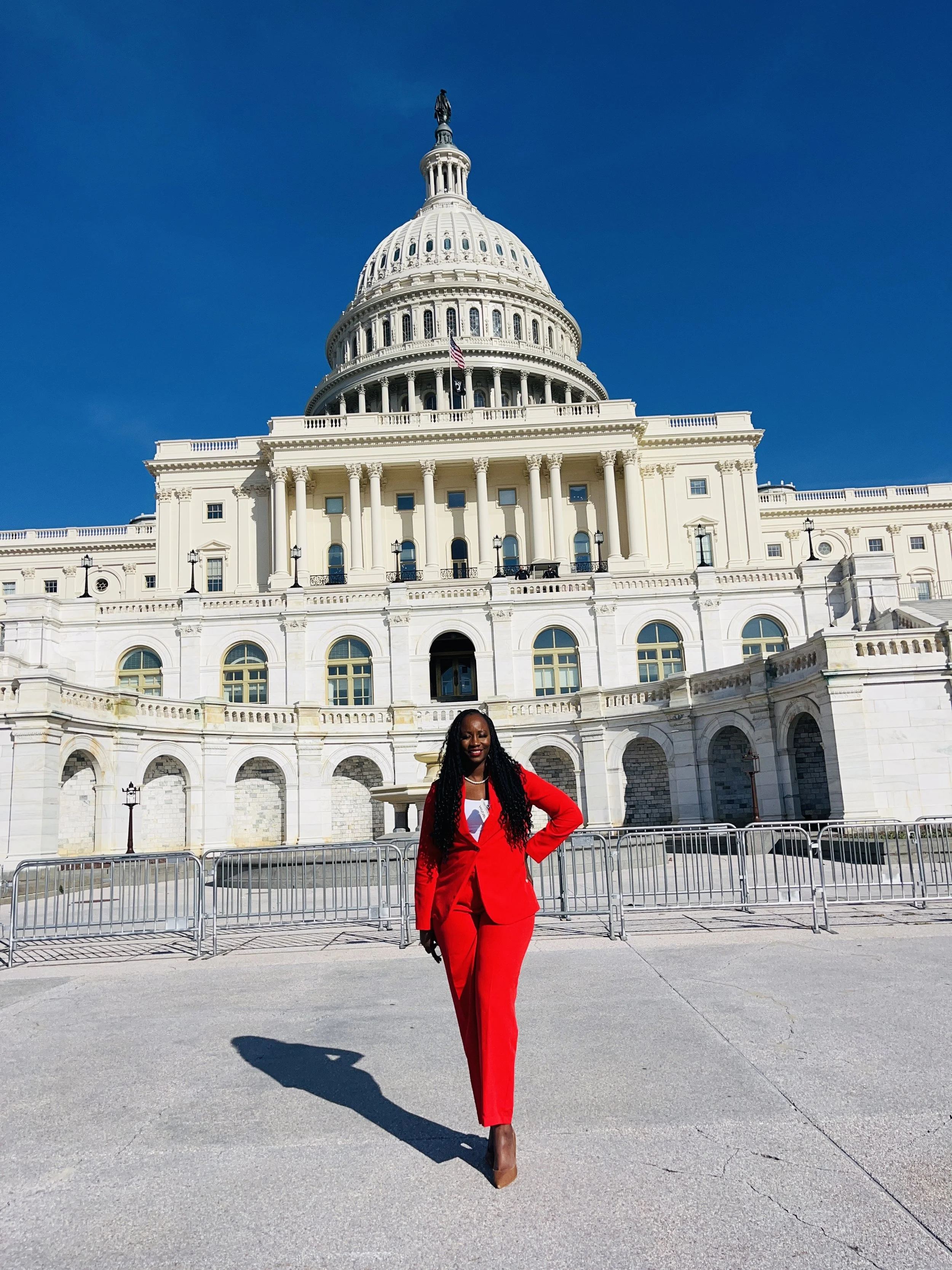 Woman in red suit standing in front of the United States Capitol building.