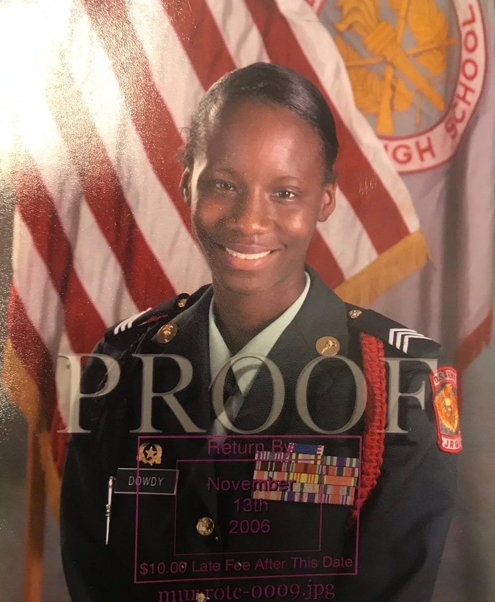 A smiling African American female firefighter in uniform, standing in front of American flag and fire department banner.