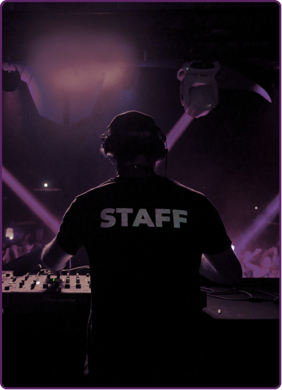 Person en t-shirt avec le mot 'STAFF' à l'arrière, travaillant à un DJ avec un casque dans une ambiance sombre et lumineuse de discothèque ou concert.