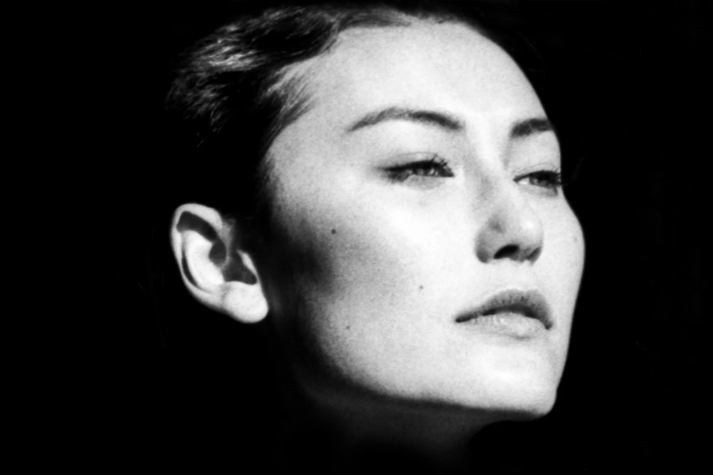 Close-up black and white portrait of a woman's face with makeup, focusing on her closed eyes, eyebrows, and lips.