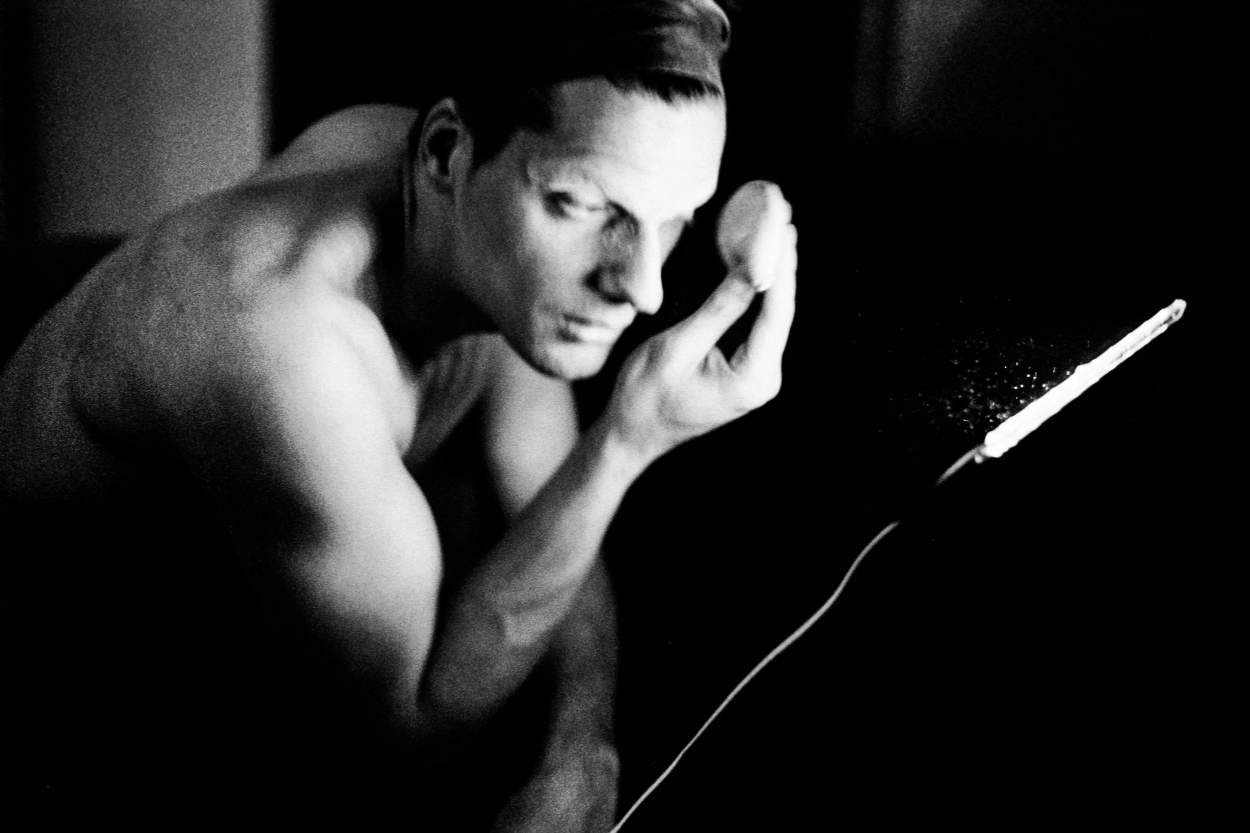 Black and white photo of a woman with short hair rubbing her face with her hand, appearing to be emotional or distressed.