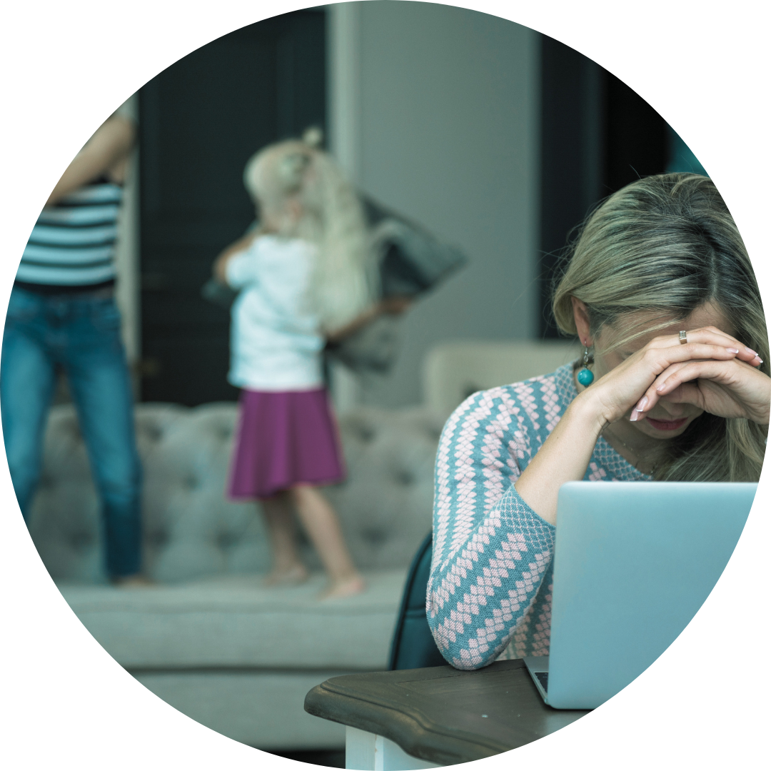 Woman-mom holding head up in front of laptop while kids play behind her