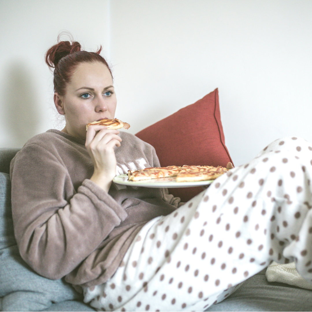 Woman eating pizza in bed winter blues