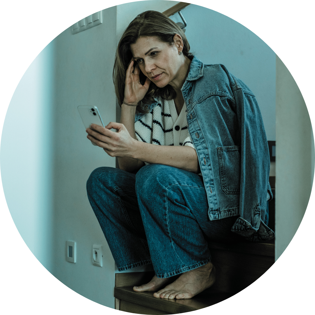 Woman sitting on stairs looking at cell phone looking stressed-perimenopause