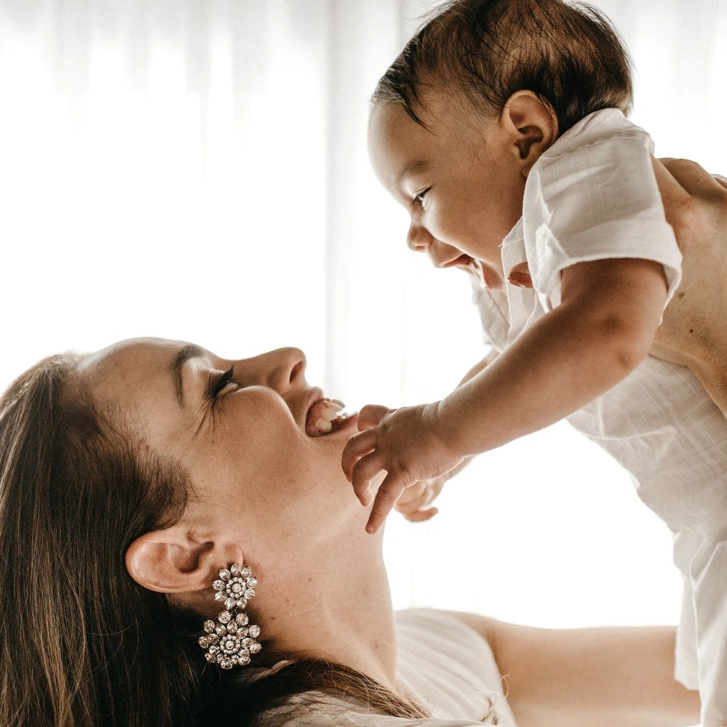 A woman holds a laughing baby above her head, smiling.