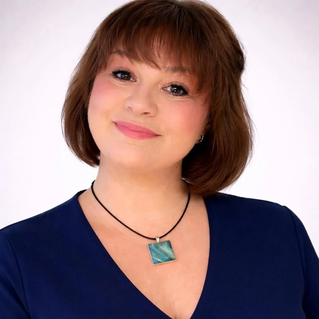 Person with short blonde hair wearing a denim jacket inside a car.