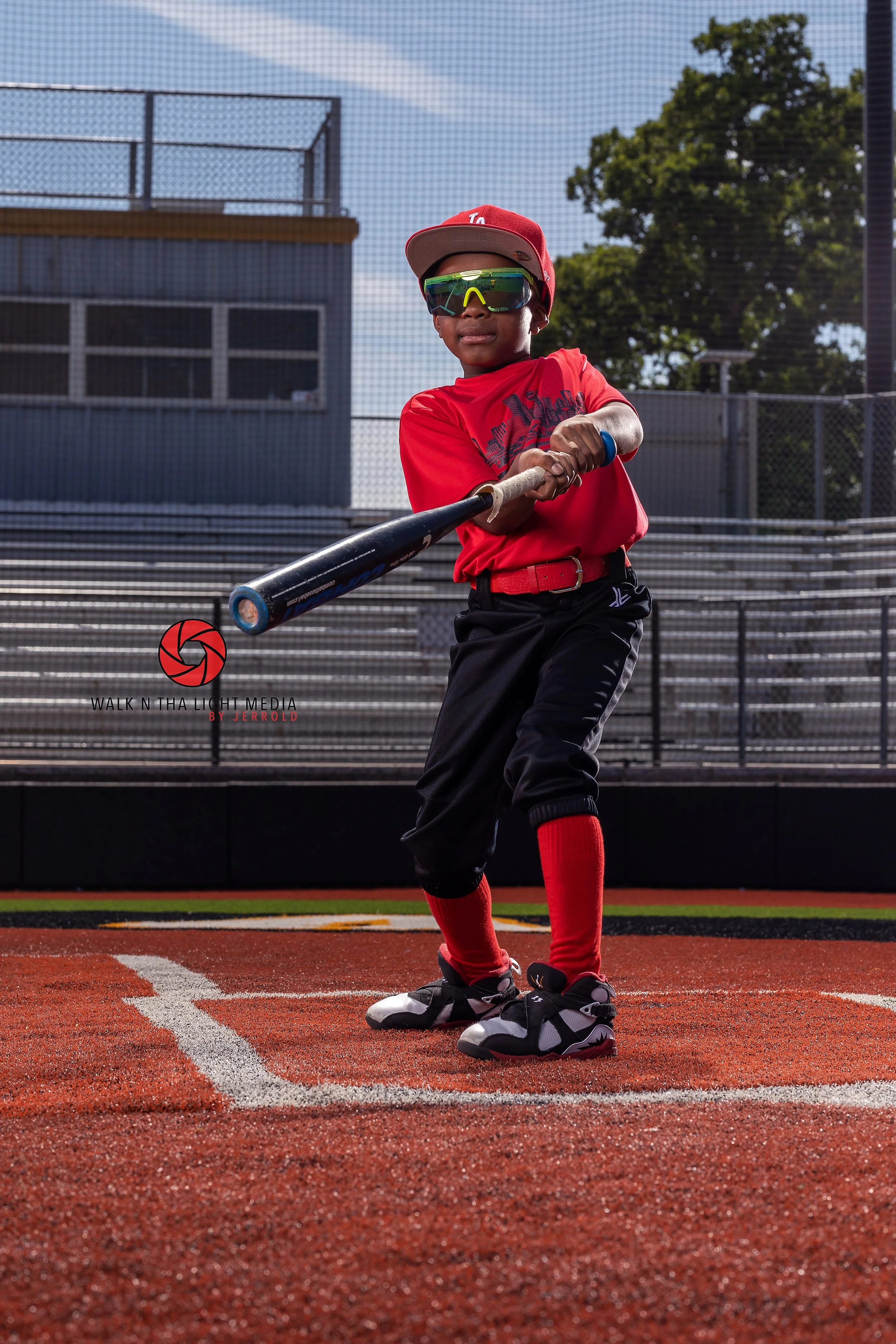 Young boy in baseball uniform swinging a bat on a baseball field