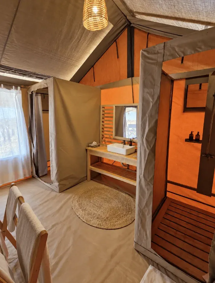 Innenraum eines Zeltes mit Badezimmer, Duschkabinen, Waschbecken, Spiegel und Vorhängen