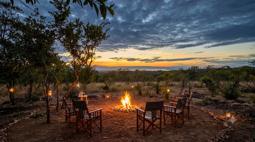 Feuerplatz mit Safaristühlen im Kijani Camp Tarangire bei Sonnenuntergang über dem Lake Burunge