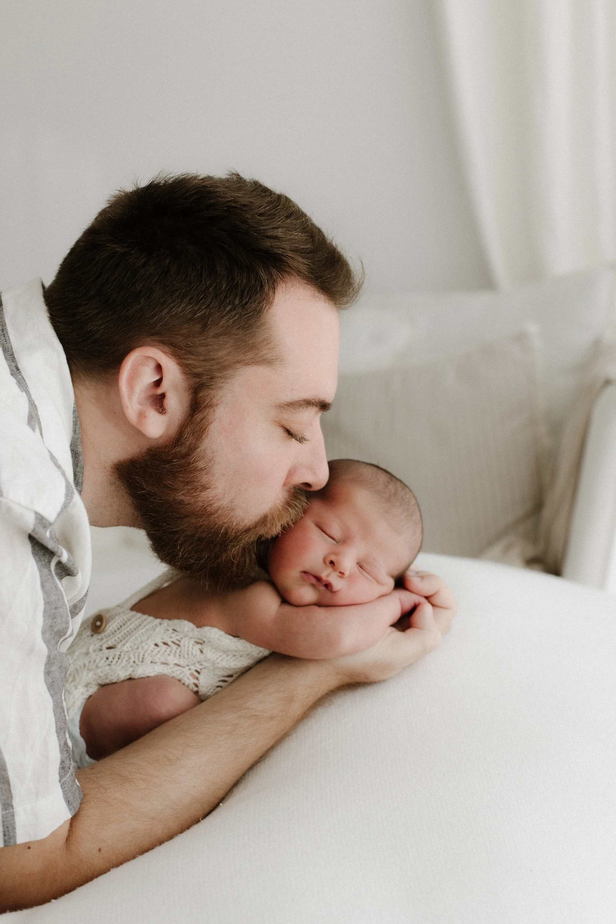Baby newborn with dad during photoshoot in a timeless white setting