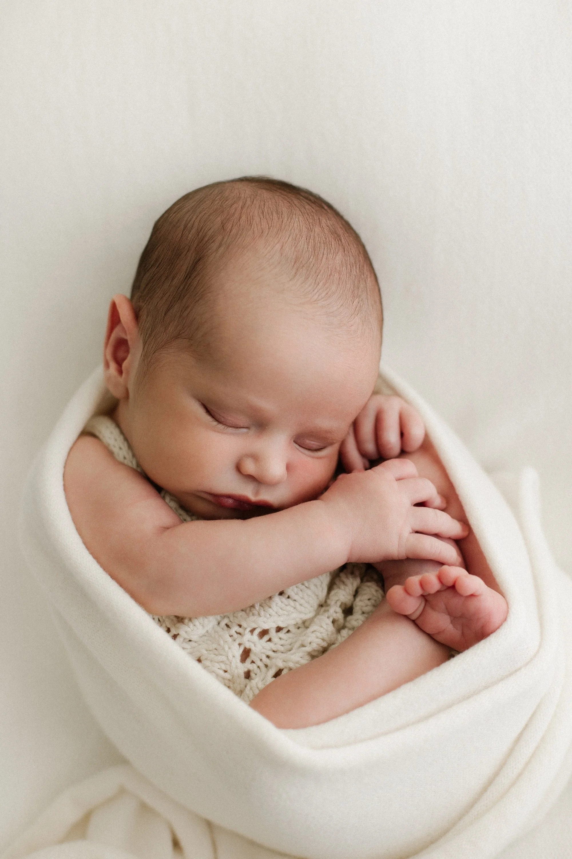 Baby newborn during photoshoot in a timeless white setting