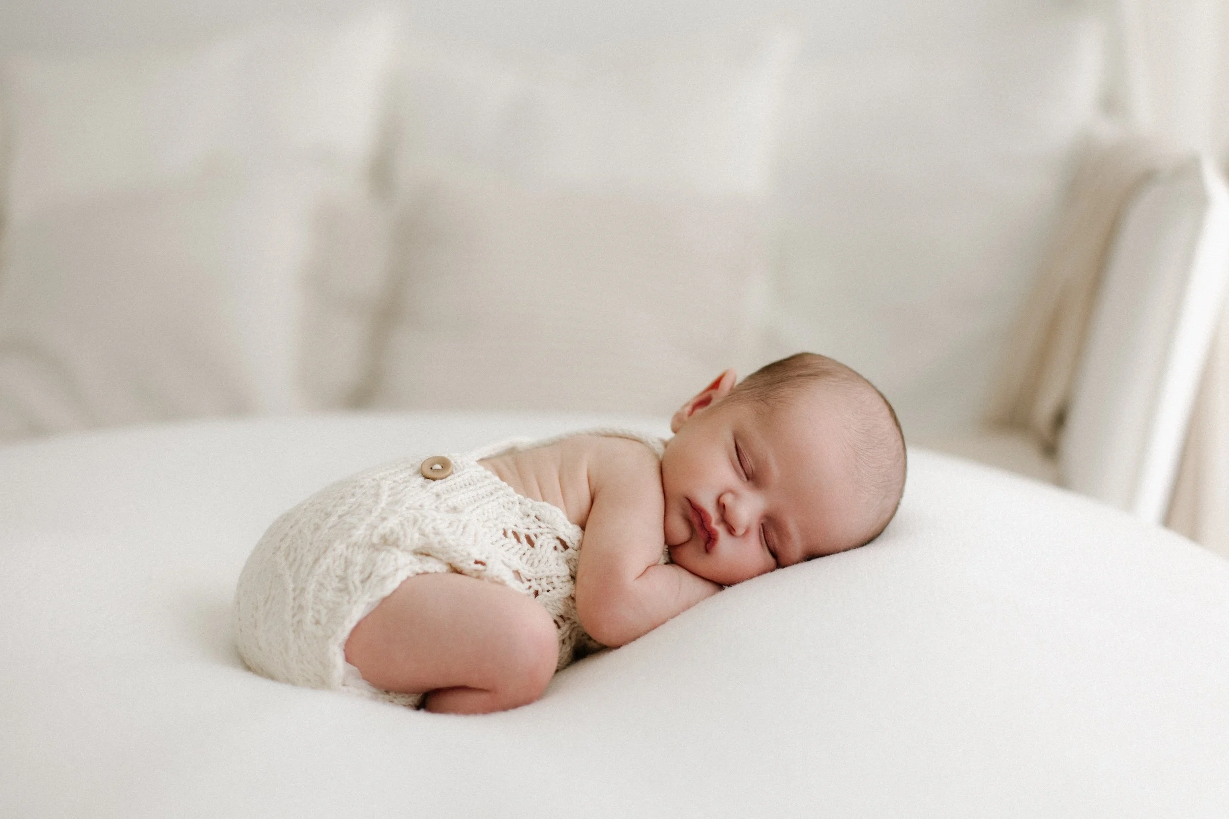 Baby newborn during photoshoot in a timeless white setting