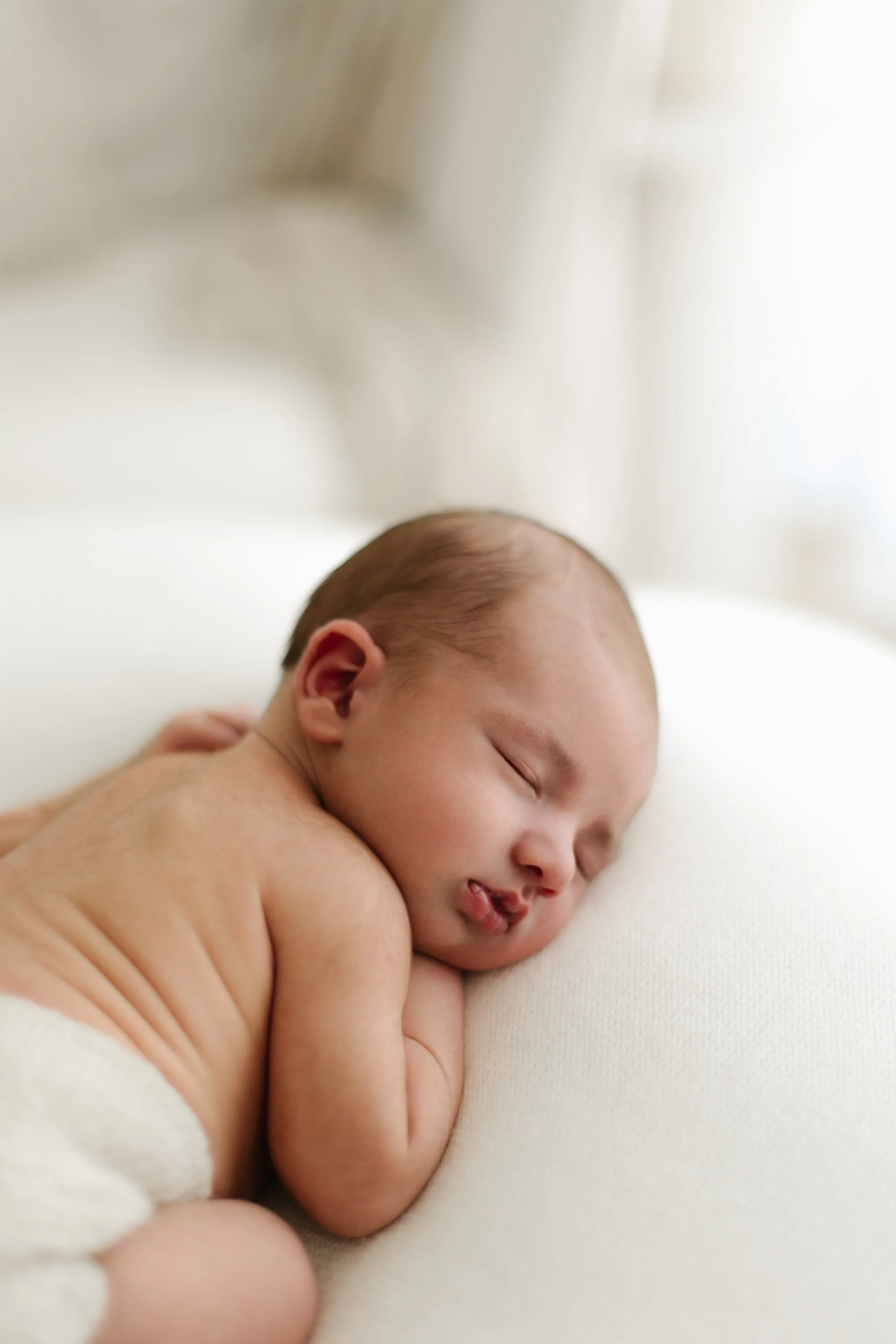 Baby newborn during photoshoot in a timeless white setting