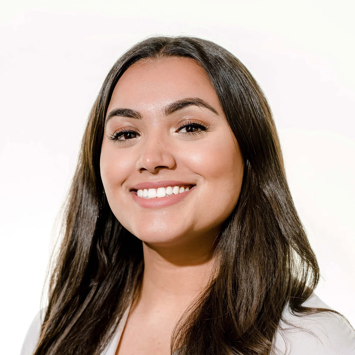 Brunette woman smiles into the camera with a white background