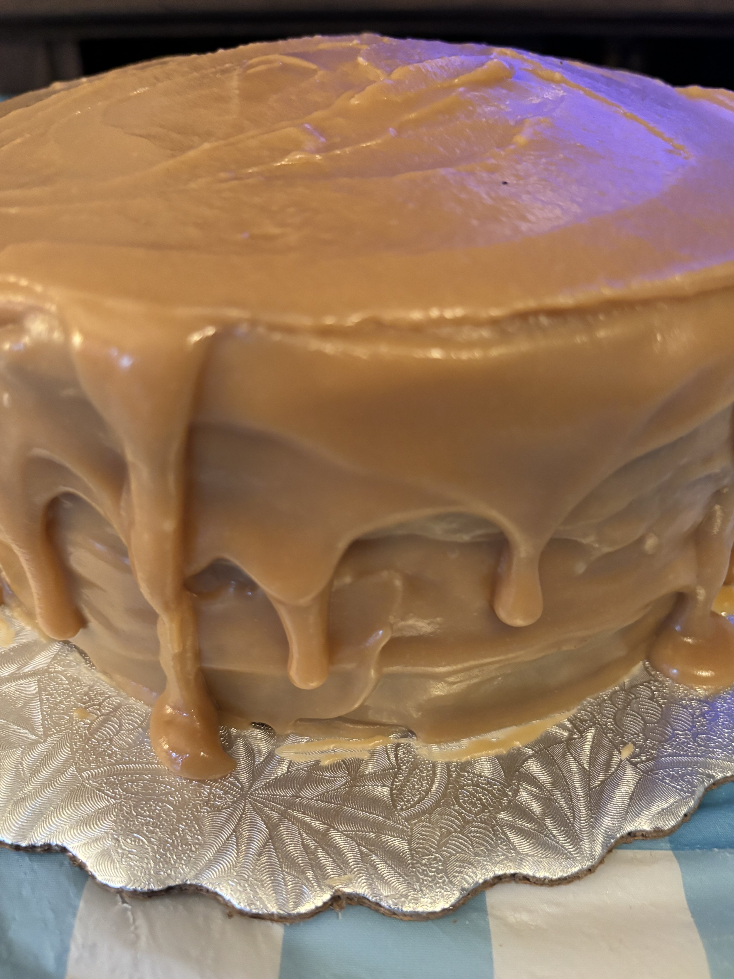 Close-up of a rich, moist three-layer caramel cake topped with smooth caramel frosting