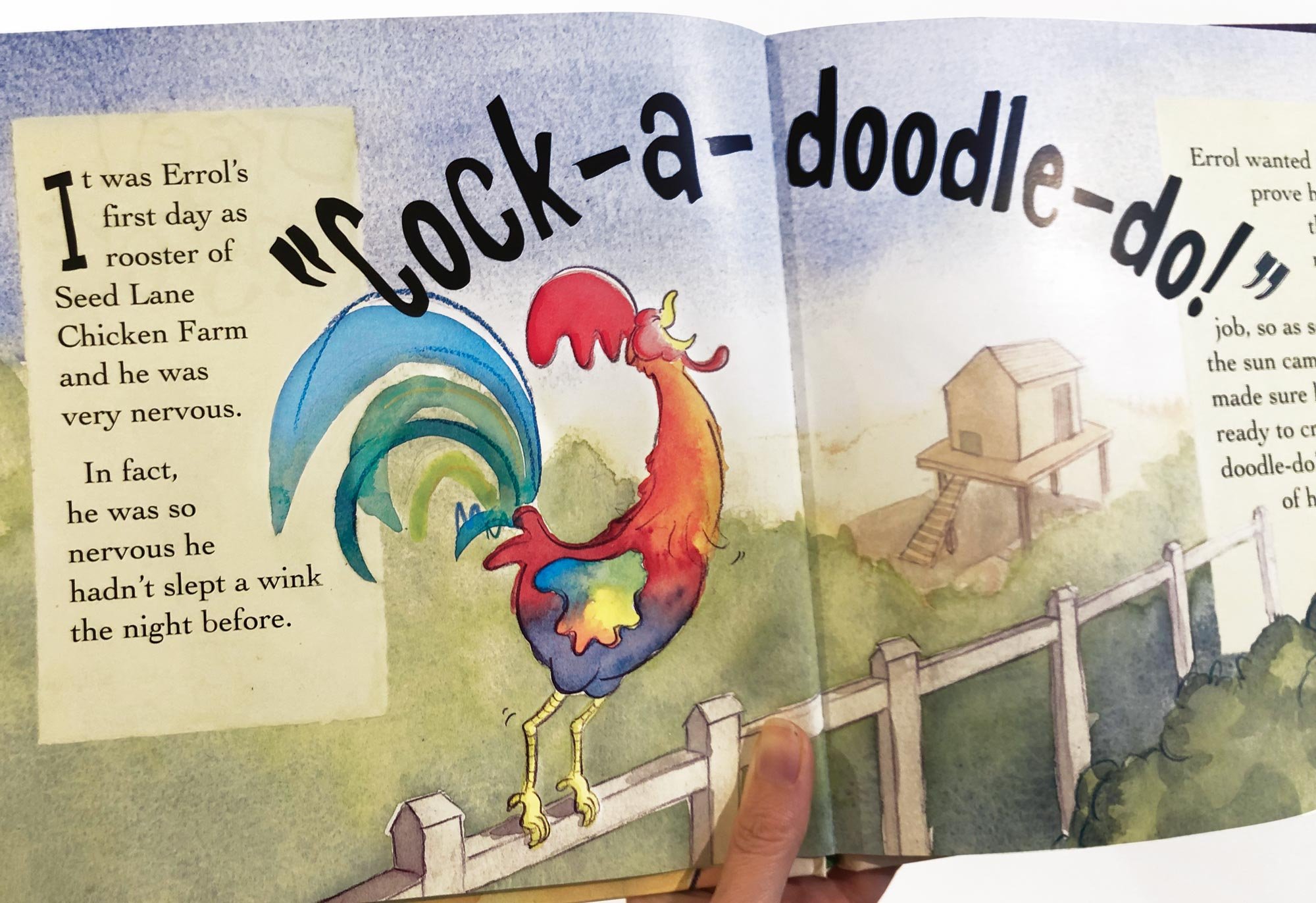 A colorful illustrated rooster standing on a fence next to a small house on stilts, with the text "Cock-a-doodle-doo!" above it.