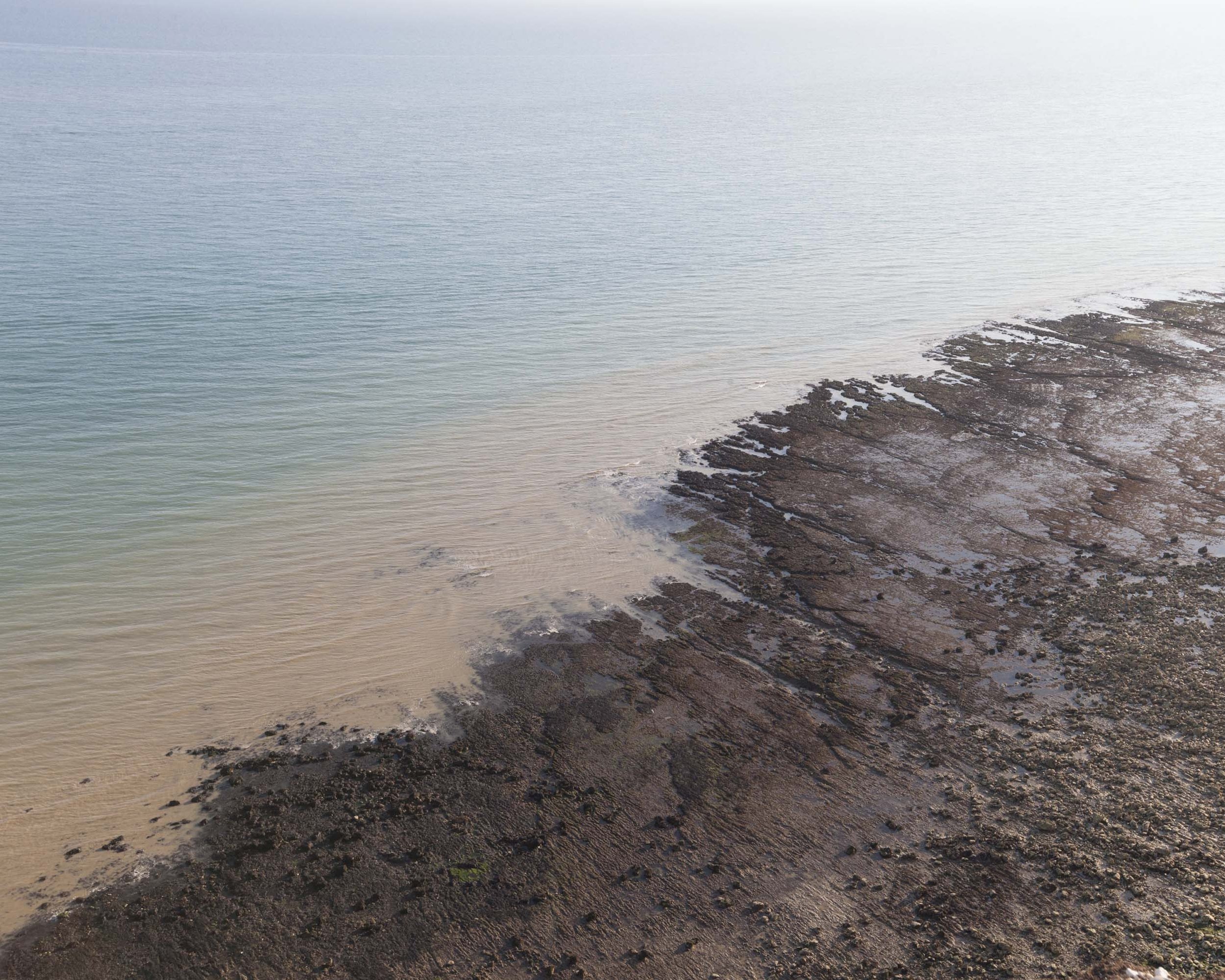 Rocky shoreline meeting calm ocean waves.