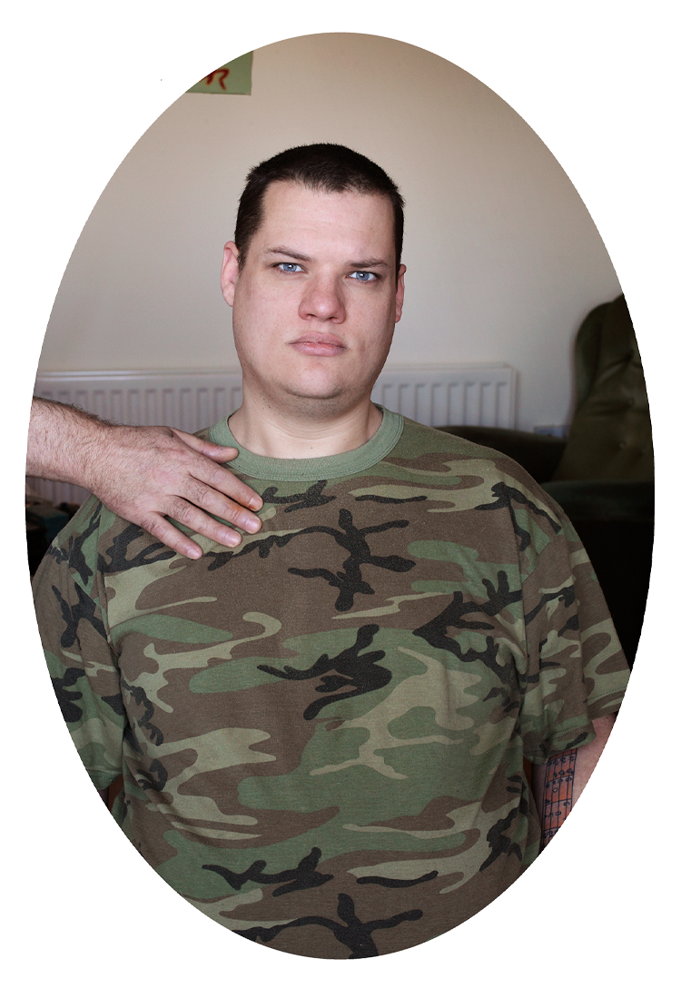 Person wearing camouflage shirt with a hand resting on their shoulder.
