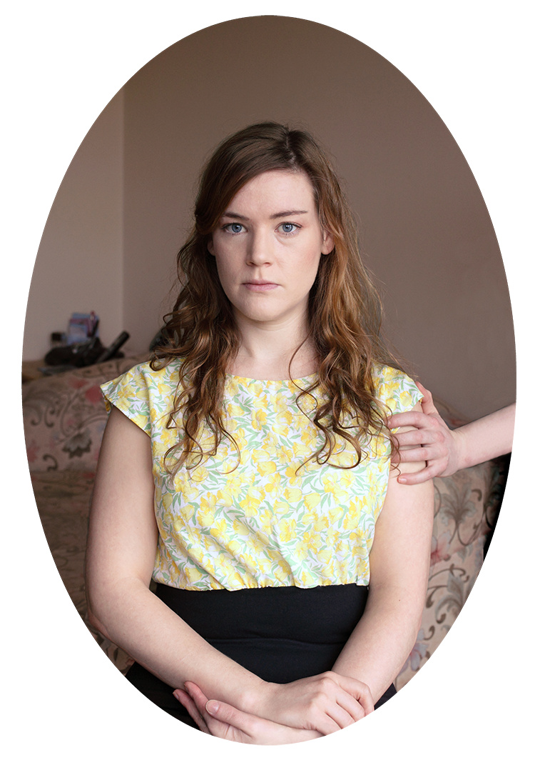 Woman in floral blouse sitting on couch with supportive hand on shoulder