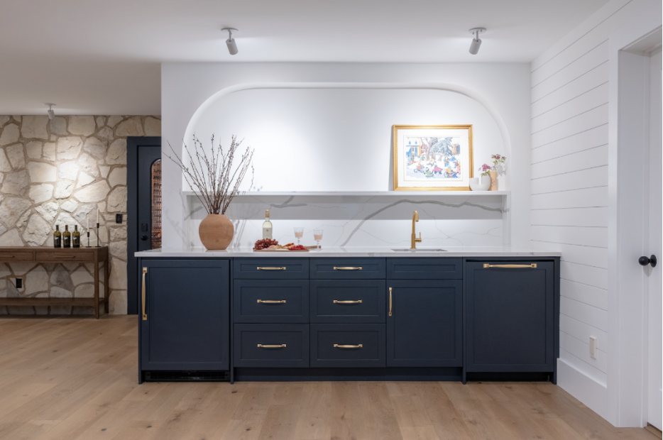 Ceiling mounted lights pinpoint art and highlight the curved wall design. At the same time they offer a layered option along with recessed lighting.