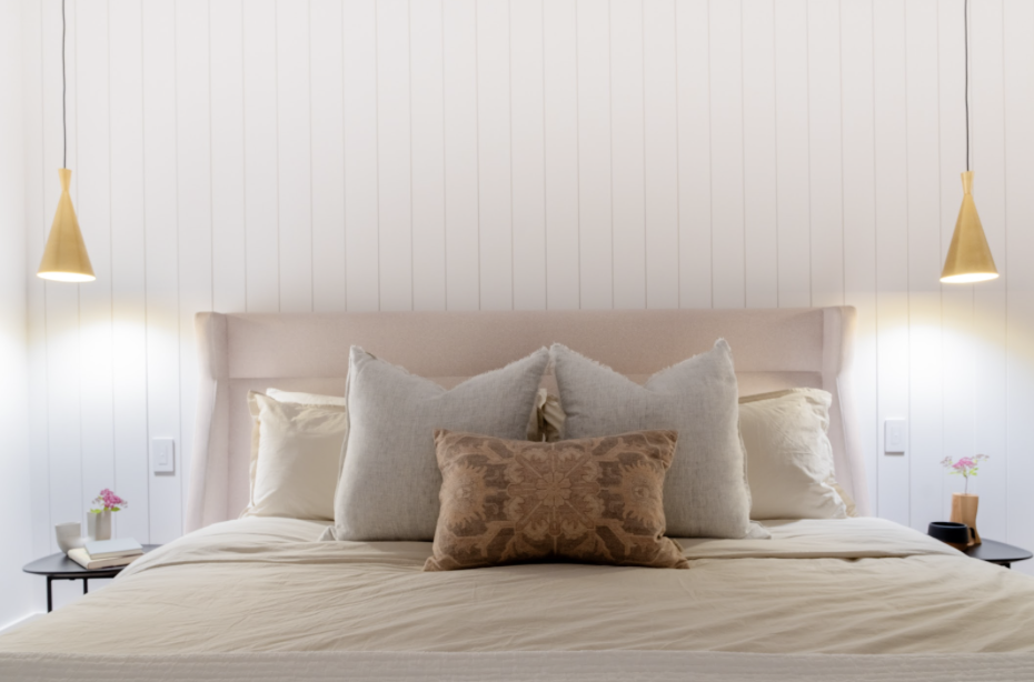 Two gold hanging lights match and provide uniformity to flank the bed in this guest room. Creating harmony with matching styles, allows for flow and consistency in a small space.