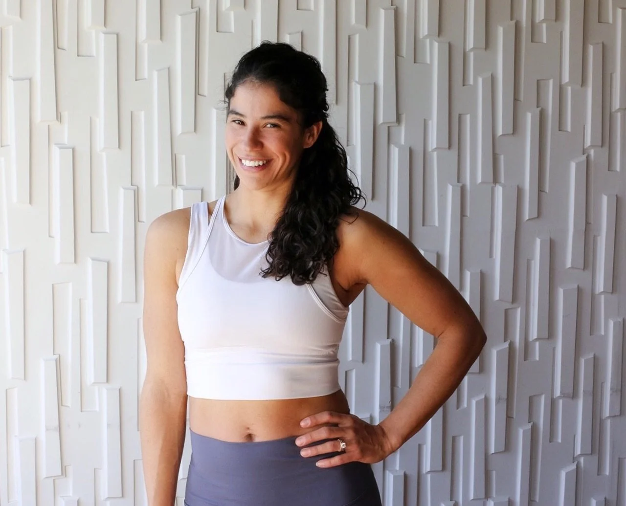 Woman smiling in athletic wear against textured wall