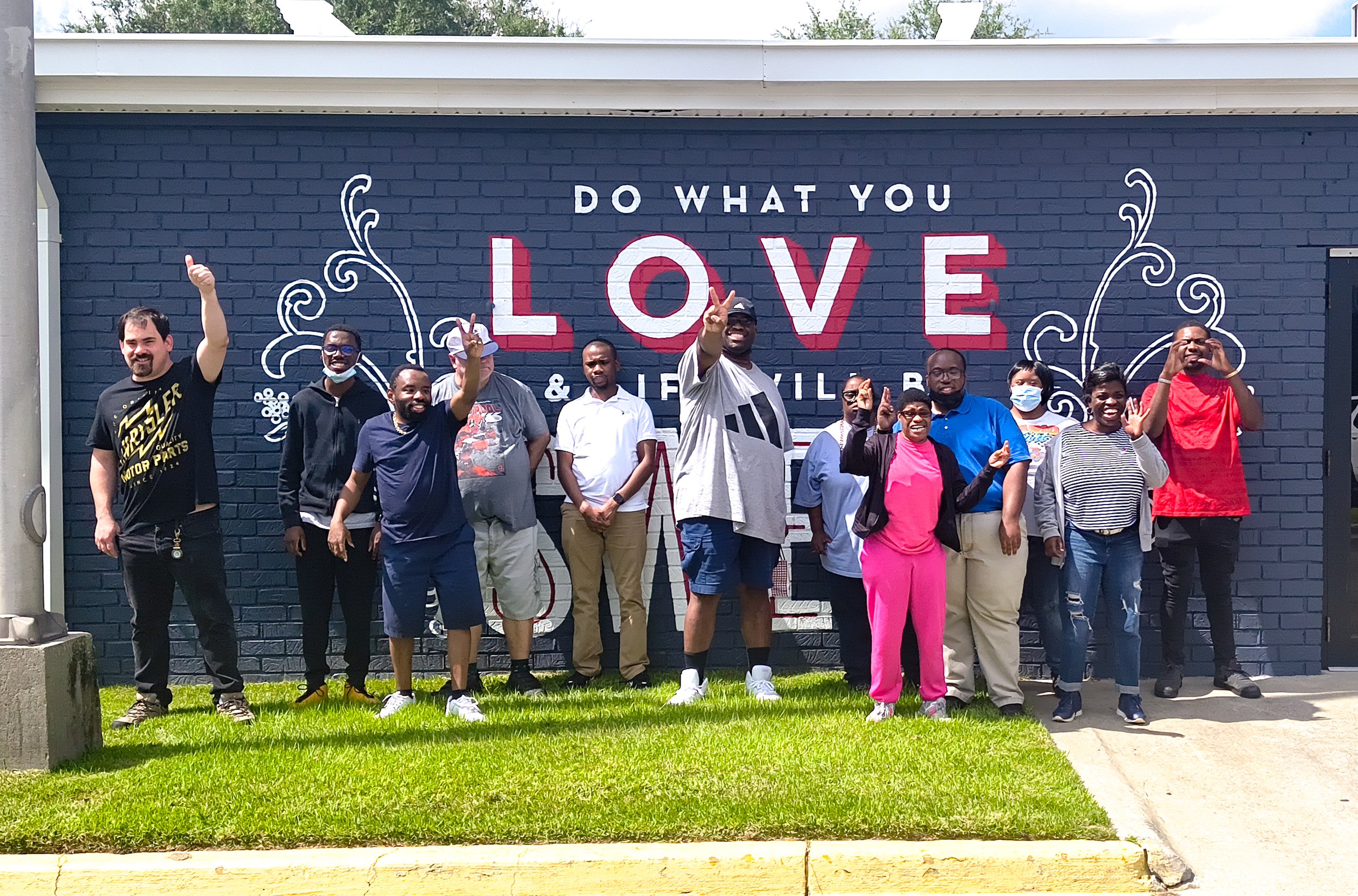 Image shows a young woman in a red shirt and a young man in a green shirt and grey jacket smiling in an EmployAbility classroom