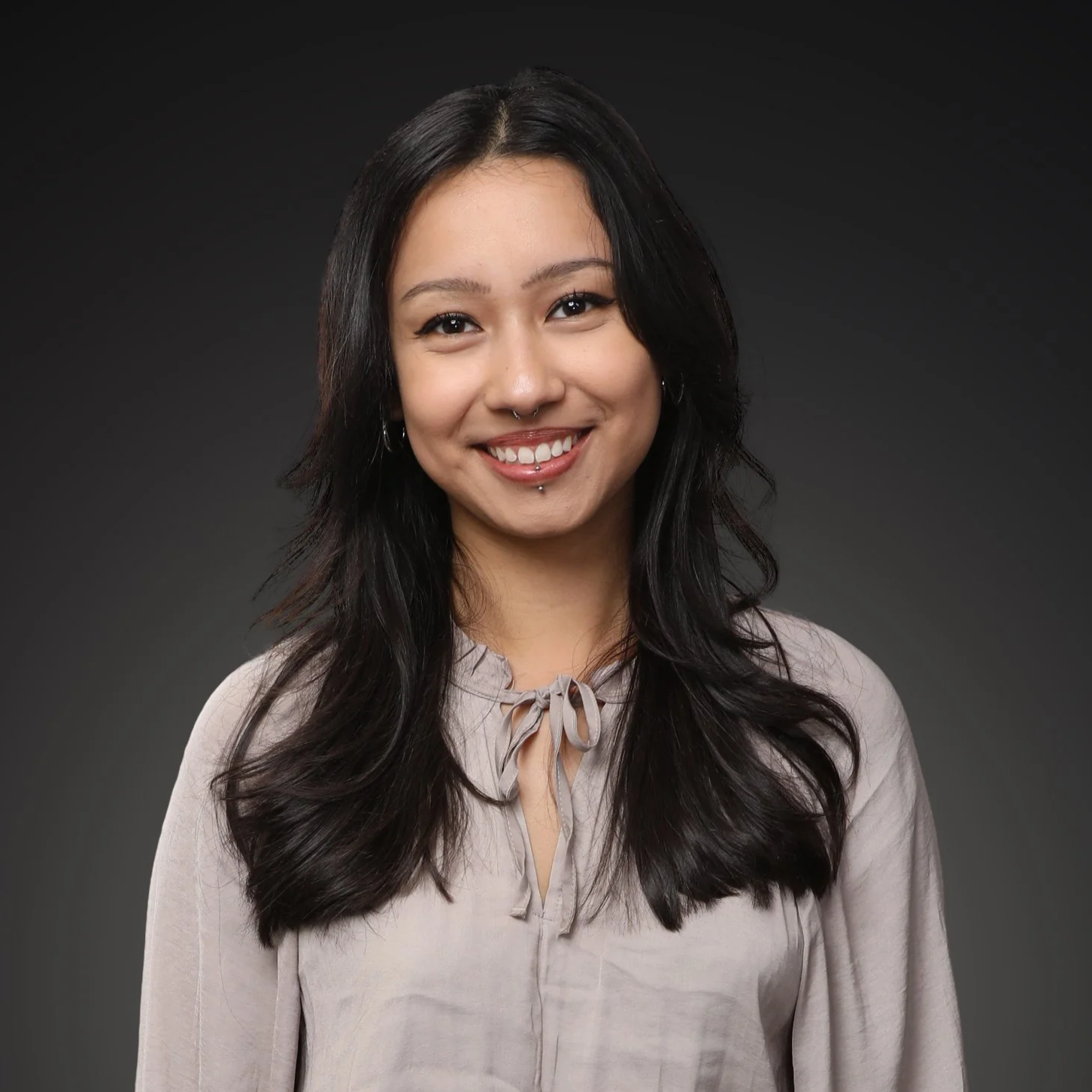 Portrait of a smiling woman with long dark wavy hair, wearing a patterned black and white top, earrings, and facial piercings I Scott Brown Properties I Denton, TX