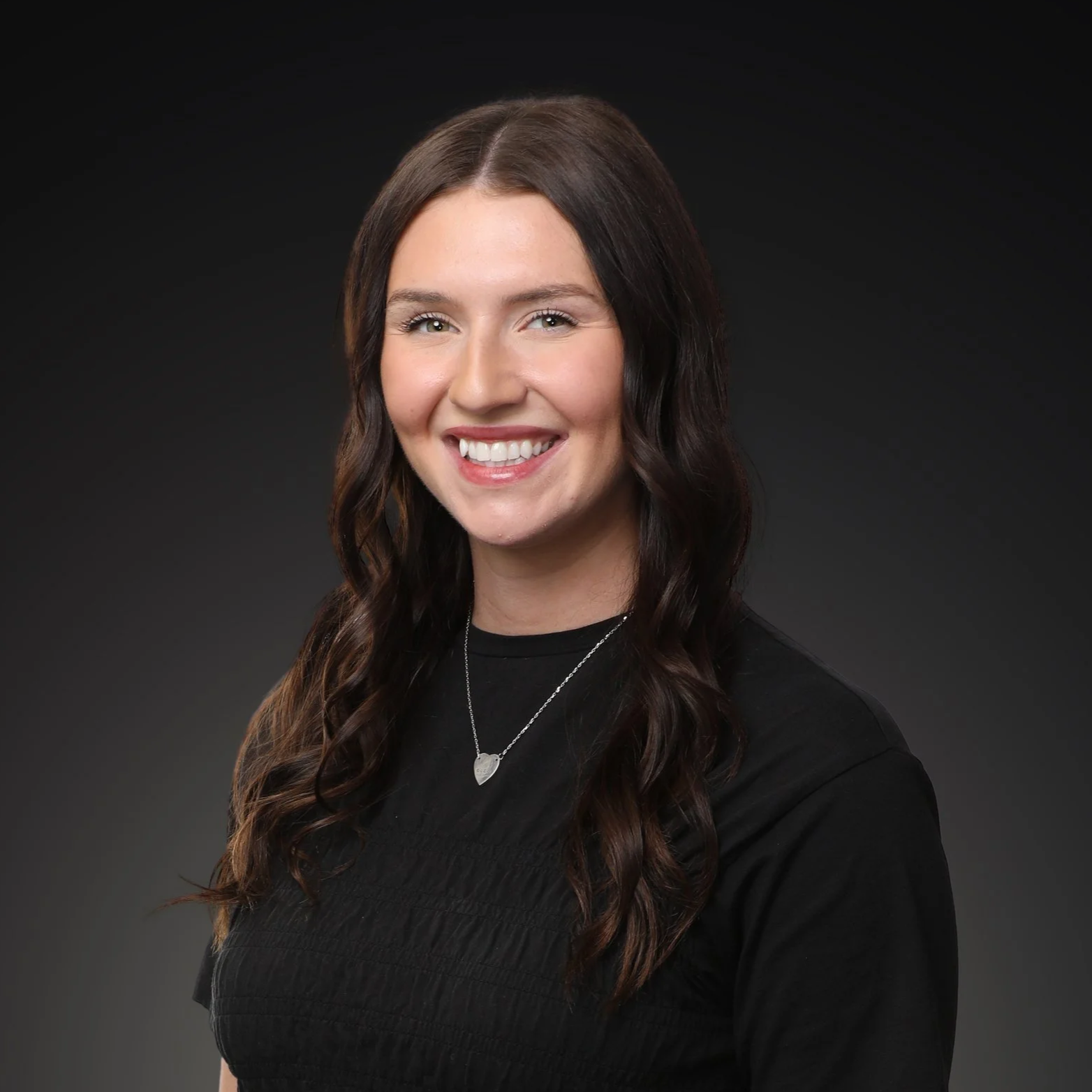 A smiling woman with long dark wavy hair wearing a black sleeveless top  I Scott Brown Properties I Denton, TX