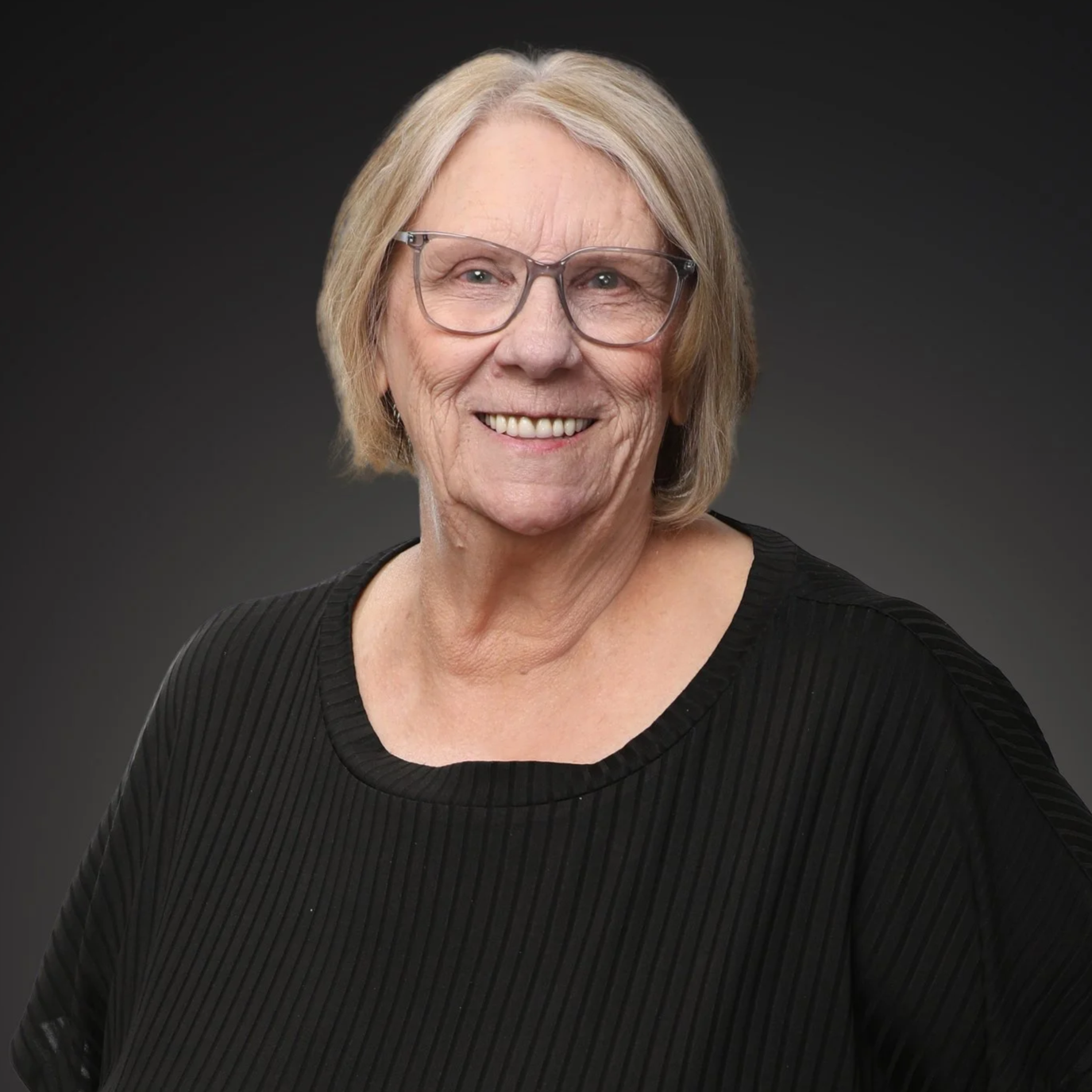 Portrait of a middle-aged woman with blonde hair, wearing glasses, a floral blazer I Scott Brown Properties I Denton, TX