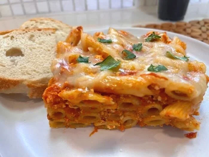 A close-up of bubbly,  vegan baked ziti cut a pan of baked ziti.