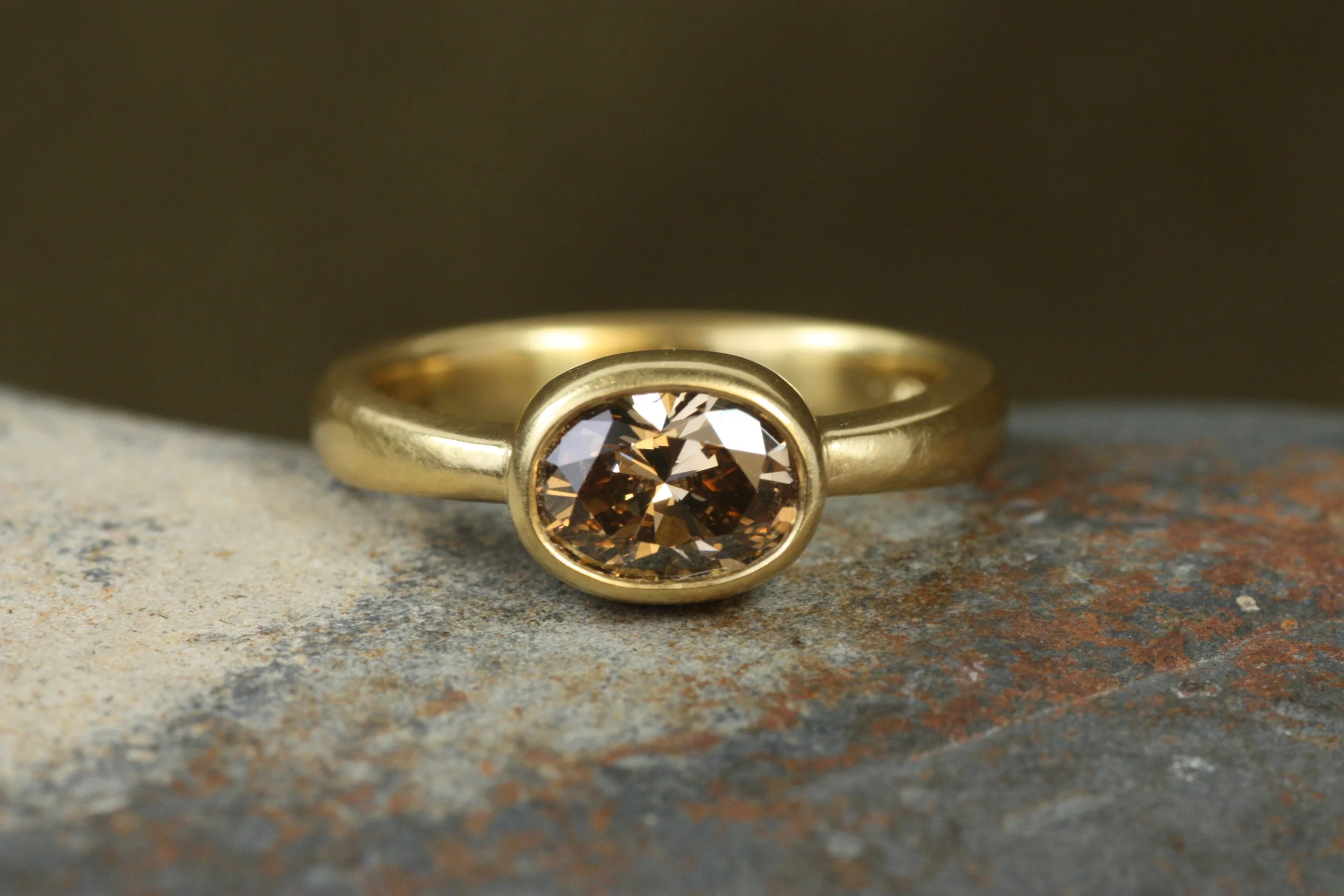 oval brown diamond bezel engagement ring on rock