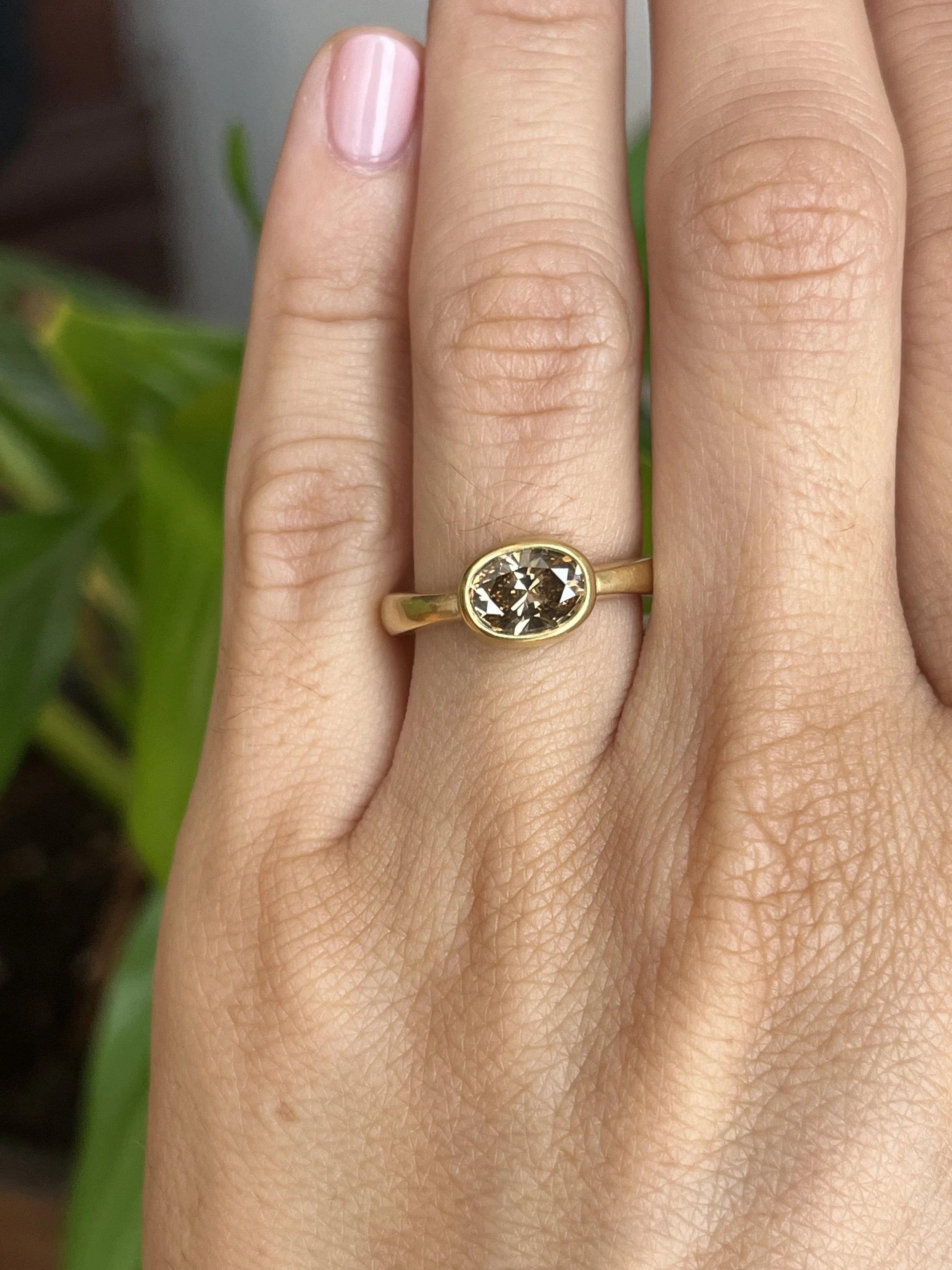 oval brown diamond bezel engagement ring on hand