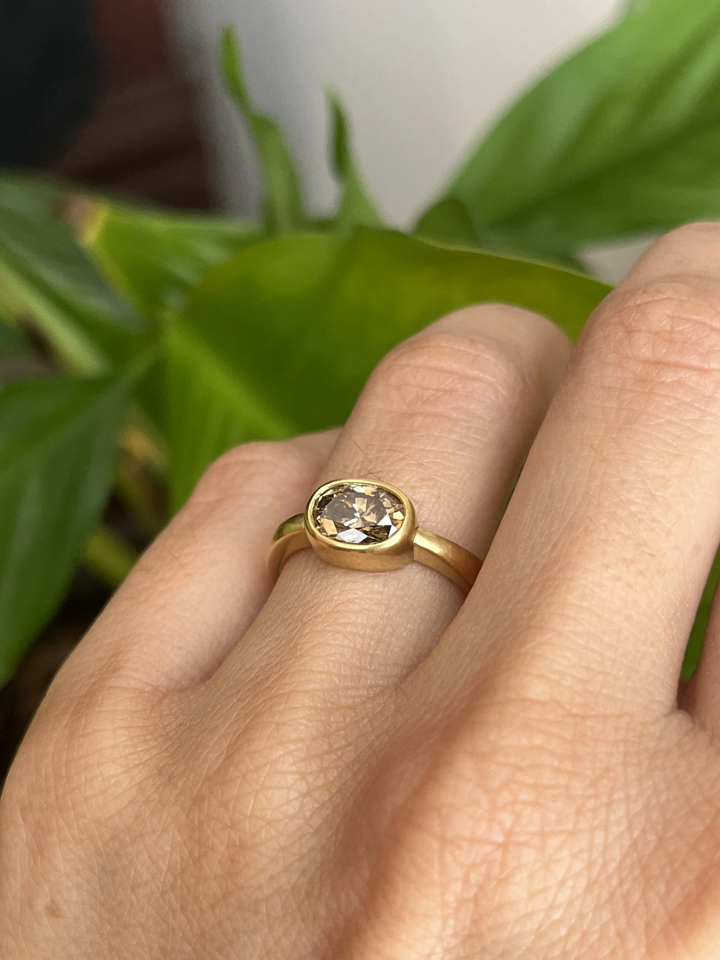 oval brown diamond bezel engagement ring on hand
