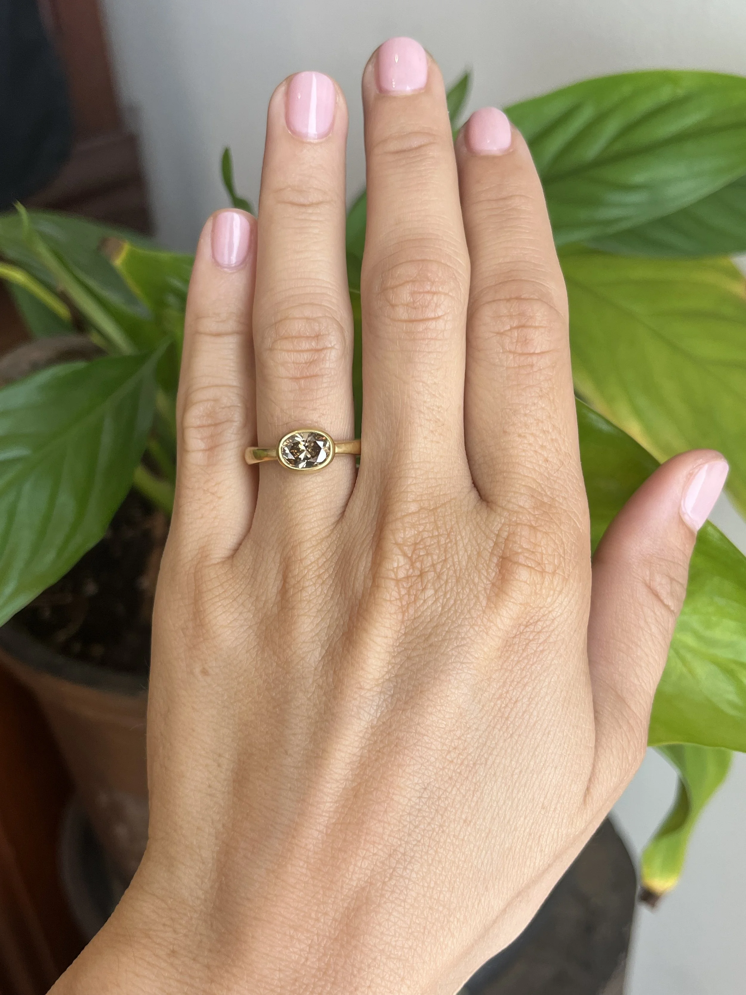 oval brown diamond bezel engagement ring on hand