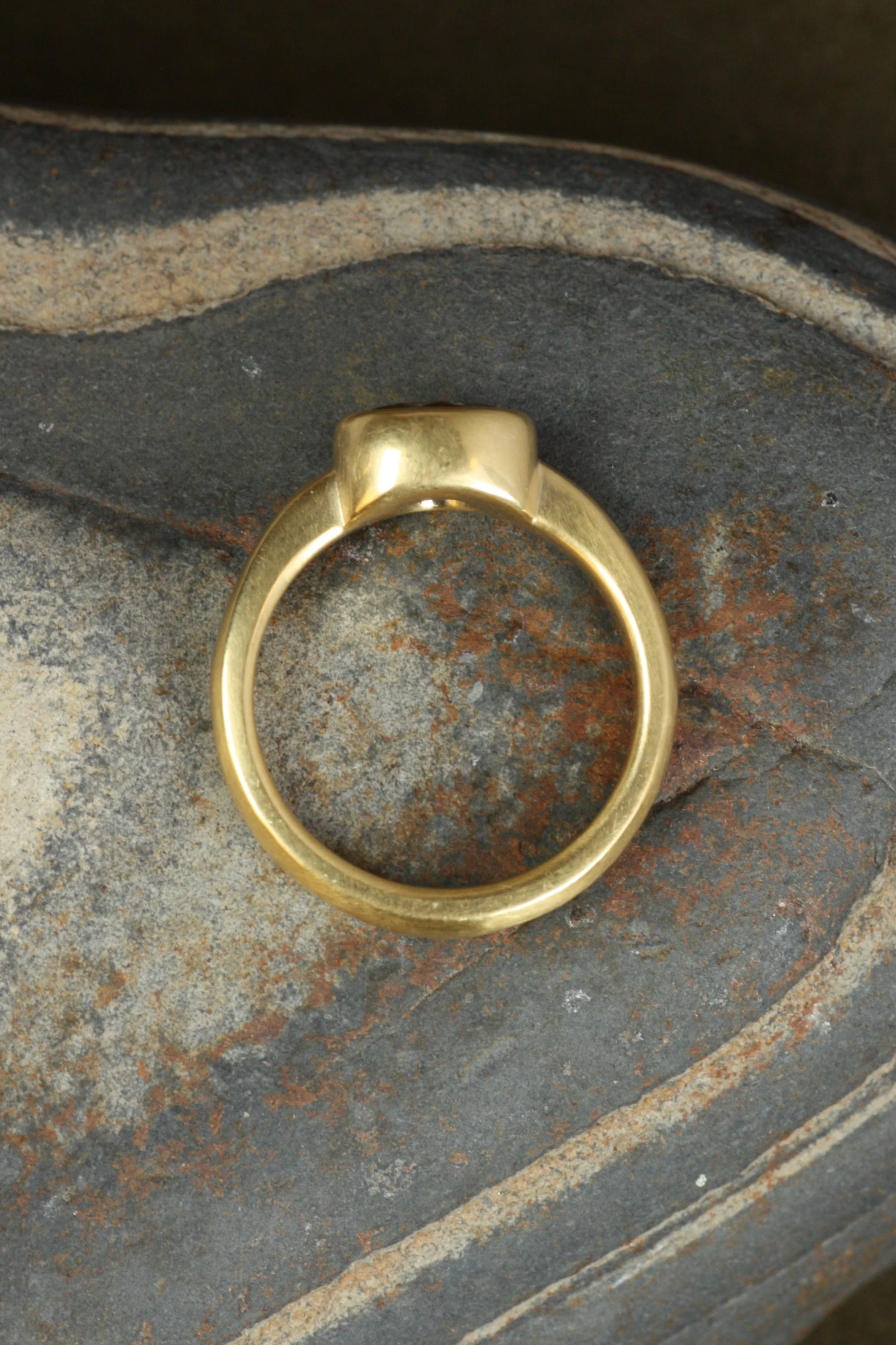 diamond bezel engagement ring laid on side on rock