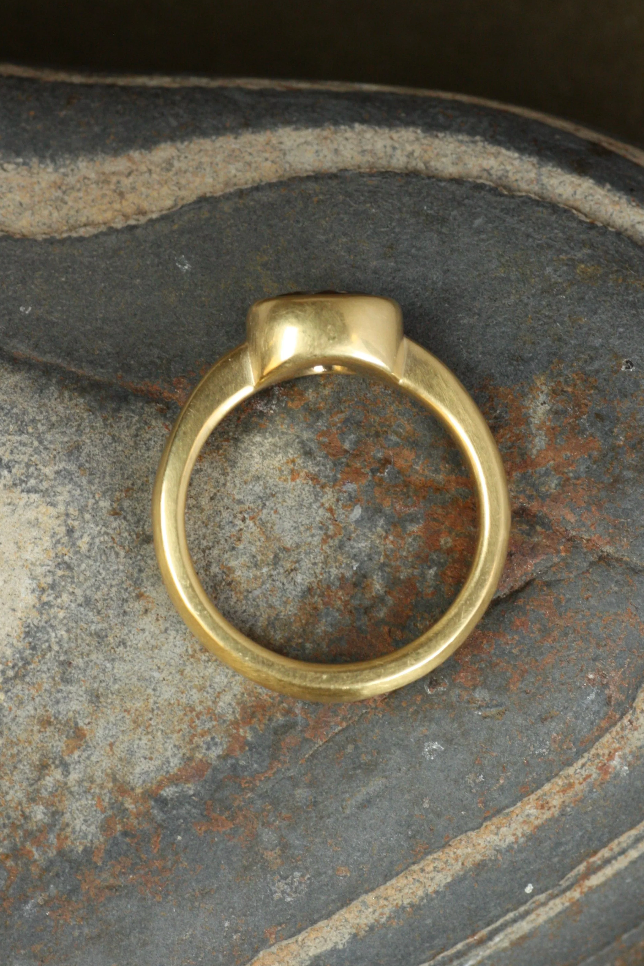 diamond bezel engagement ring laid on side on rock