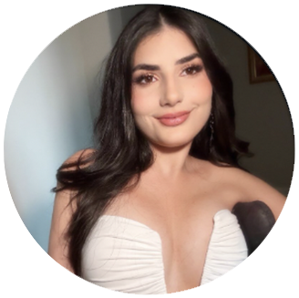Photo of Elle- woman with long dark hair in a white strapless top smiles in front of a grey background.
