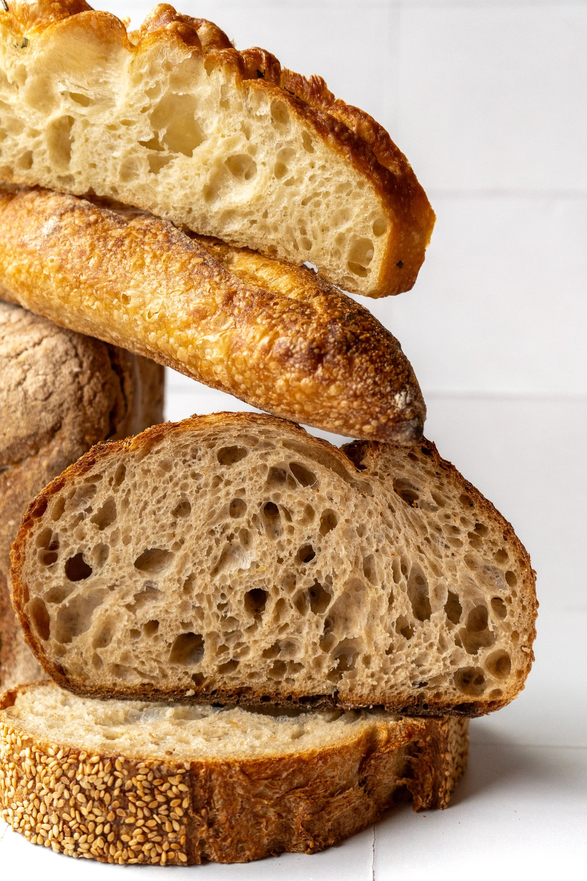 Close-up of various sliced breads stacked on top of each other, showing the textures and crusts of different types.